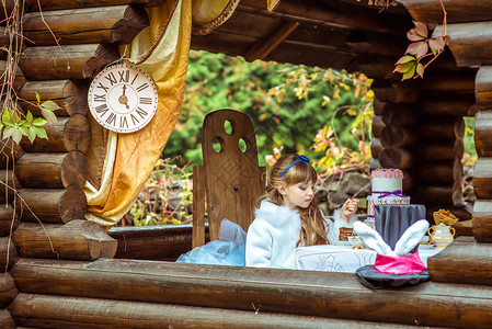 小爱丽丝眼前的景象 一个小美少女拿着一块蛋糕 在桌子上的勺子上童话微笑童年想像力文化女性发型野餐魔法乐趣背景