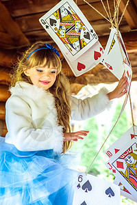 一个美丽的小女孩 玩耍和跳舞 用大牌在桌上打牌的游戏女性灌木丛裙子冒险魔法故事创造力蓝色女孩艺术背景图片