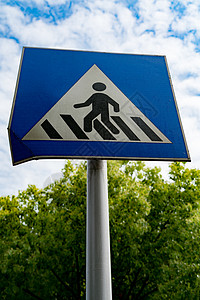 带有蓝天空和绿树的行人符号或横行标志金属危险警告穿越按钮信号天空城市交通运输背景