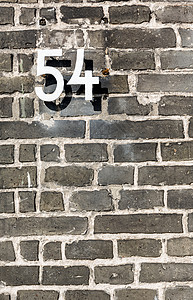 灰色砖墙上的金属门牌号 54高清图片