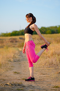 年轻的健身女人在野生公园里伸展 做伸展运动的女赛跑者 健康的生活方式概念衣服训练场地活力赛跑者草地运动员公园娱乐慢跑者背景图片