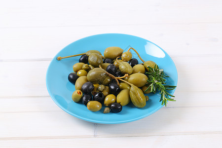 绿色的 黑色的橄榄 以及有果和的果实伴奏浆果食物沙拉盐渍迷迭香盘子蓝色雀跃背景图片
