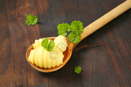 勺子上的黄油卷曲心结厨房卷发食品传播背景奶制品用具炊具香菜食物背景图片