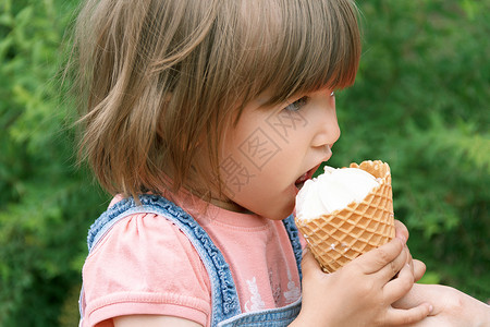 可爱的女孩在吃冰淇淋头发金发白色女性女士公园孩子地平线背景图片