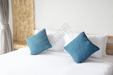 情人酒店床上白白枕头和蓝枕头 卧室有毯子休息织物奢华酒店家具情人房间棉被风格装饰背景