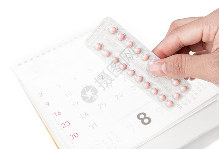 排卵紧紧手握着避孕药片 日历日期在后面背景