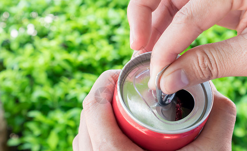 近身女人的手打开可乐 能与自然绿色黑地白色金属男性罐装自拍饮料苏打食物背景图片