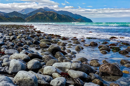 曼加马乌努附近海滩绿色石头多云灰色波浪白色格式蓝色水平山脉背景图片