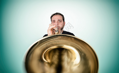 有趣的男人在吹号角玩家音乐训练男性惊喜成人艺术黄铜金子音乐家背景图片