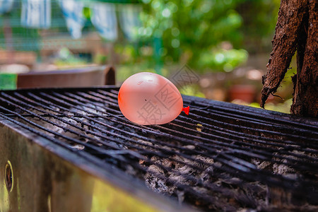 热烤炉上装满了水的水的气球橙子乐趣金属实验科学烧烤后院炙烤液体公园背景图片