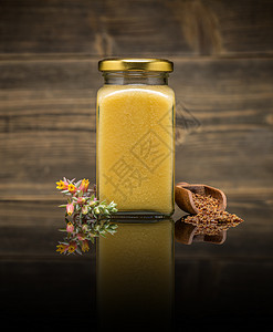 黄色玻璃罐子里的蜂蜜静物产品颗粒蜜蜂蜂房养蜂业药品反射玻璃花粉背景