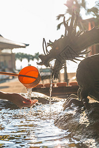 雕塑龙吐水阳光下有龙雕像的竹竹子水泉背景