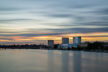 瑞典Umea市下城日落城市乌梅树木天空橙子建筑物多云日落绿色背景图片