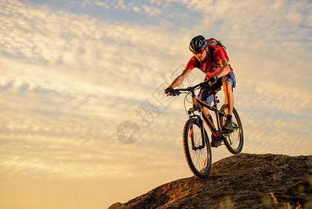 红色骑车的赛车女赛车员 在日落时下岩礁 极端运动和概念天空娱乐男人乐趣蓝色耐力赛踪迹岩石爬坡骑士背景