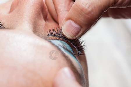 睫毛胶水贴近一个化妆师 把假睫毛用在织物上眼睛睫毛造型艺术家沙龙手指程序魅力男人黑色背景
