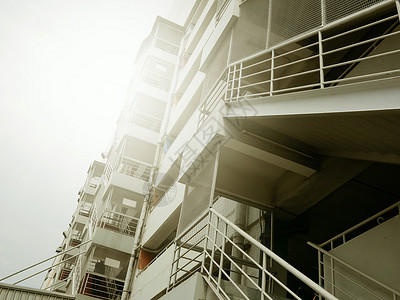 建筑物外有阳光的防火梯子和外面建筑背景图片