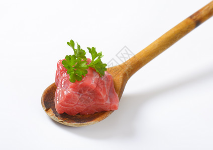木制勺子上的生牛肉片立方体红肉牛肉食物牛扒炊具背景图片