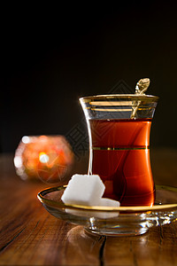 传统玻璃中的土耳其茶茶色红色文化飞碟火鸡液体盘子背光棕色黑色背景图片