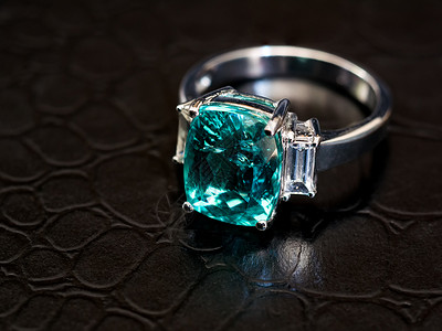 用白色钻石特写绿色宝石环和白色钻石石头金属礼物反射首饰珠宝皮革黑色色石奢华背景图片