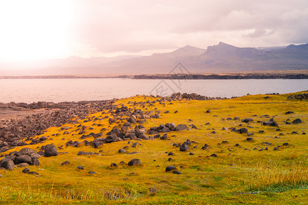 冰岛斯奈费尔斯半岛具有绿平原和岩石海岸的火山风貌半岛戏剧性海洋全景蓝色阳光锥体土地山脉爬坡背景