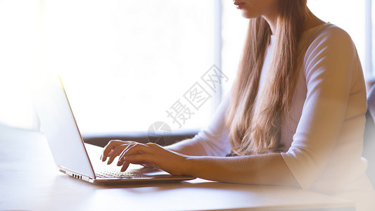 在大窗口前的笔记本电脑键盘上贴近女性手打字图像互联网购物成人铅笔商务太阳工人职场人士窗户背景图片