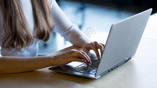 在大窗口前的笔记本电脑键盘上贴近女性手打字图像工人成人学生工作商务职场桌子窗户衬衫购物背景图片