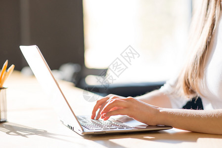 在大窗口前的笔记本电脑键盘上贴近女性手打字图像成人女孩职场互联网桌子窗户人士商业技术学生背景图片