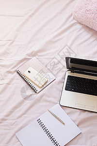 粉红色床单上的笔记本电脑和智能手机 平躺风格的自由时尚家居女性气质工作区背景图片