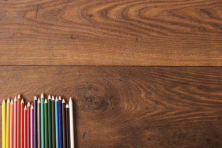棕色木桌背景上的彩色铅笔 彩色铅笔框架在木头上 带有文本复制空间的可用空间大学工具桌子彩虹绘画艺术教育染色调色板橙子背景图片