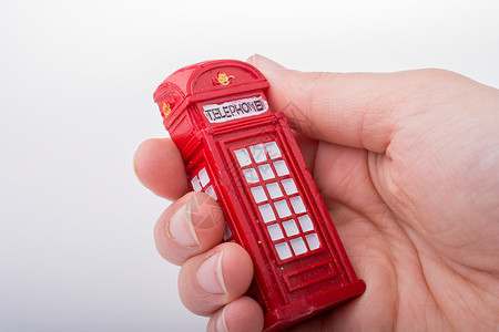 手持白色背景的电话亭 手持英语公用电话城市电话盒子红色背景图片