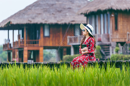 雄镇东南在老挝的Vang Vieng与绿稻田一起坐在木路上的年轻女子游客旅游冒险旅行热带全景场景空气气球文化背景