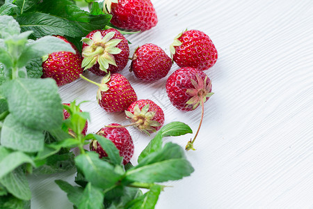 新鲜混合红草莓 白木上绿色薄荷背景图片
