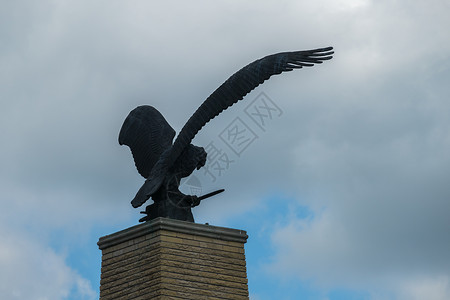 鸟雕像一只鹰雕像的雕像 有张开的翅膀 对着阴云多云的天空背景