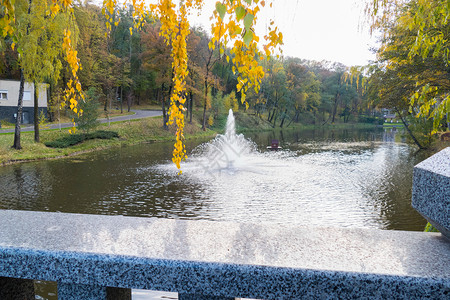 公园喷泉Marble 灰白光滑的铁轨对着一个大型装饰湖背景