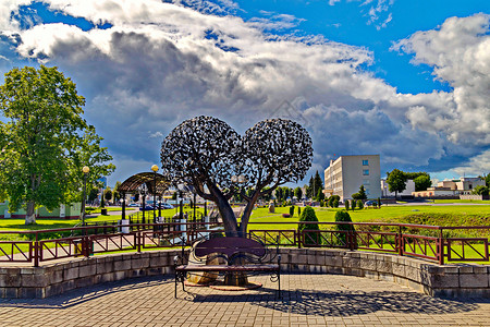 以两球形状的铁树 和在公园中的坐椅 与美丽的天空相对;背景图片