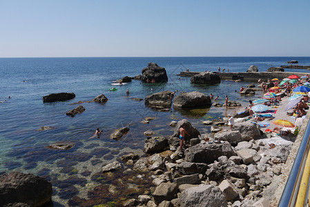 观光客 躺在海滩上 旁边的巨石堆 远到大海背景图片