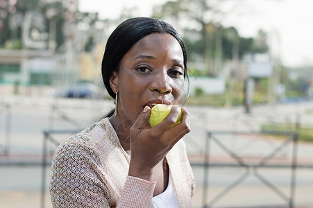 年轻女人吃苹果黄色女士绿色背景图片