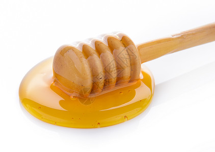 带蜂蜜的木制蜂蜜糖浆勺子黄色液体白色食物背景图片