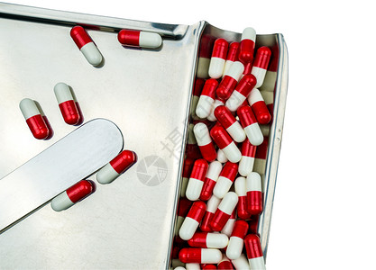 在不锈钢药物托盘上分离的红色 白色抗生素胶囊药丸的顶部视图 具有剪切路径 耐药性概念 合理用药搭配背景图片