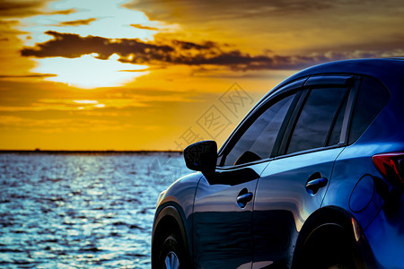 日落时分 蓝色紧凑型 SUV 车停在海边的水泥路上 采用运动和现代设计 环保技术 电动汽车技术和业务 混合动力汽车和汽车旅行活力背景图片