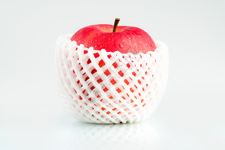 一个红苹果 皮肤上有水滴 白色防震泡沫网包裹在白色背景上 带有复制空间 健康水果和健康食品的概念 素食背景图片