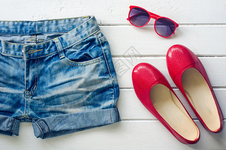 白色木制地板上女青少年的牛仔牛仔裤鞋太阳眼镜女性太阳镜服饰热情旅行旅游裙子背景图片