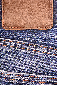 在牛仔裤背景的皮革标签 特写 棕色皮革标签 双缝线 深蓝色牛仔牛仔裤带背景图片