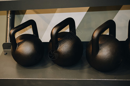 展示的金属摊上的钢铁运动杯举重健身房训练权重白色力量锻炼重量运动哑铃背景图片