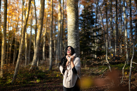 森林中年轻妇女的概况画像女孩牛仔裤心态公园树叶微笑季节自由女士旅行背景图片