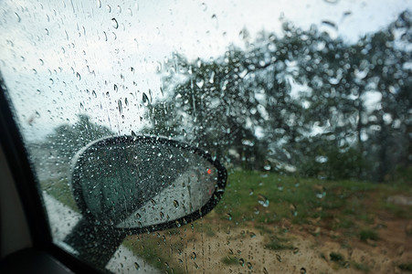 大雨从车挡风玻璃下流下来 汽车的景色是玻璃交通雨滴镜子窗户蓝色天气城市路口街道背景图片