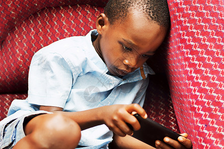 孩子在手机里玩耍青年男生闲暇椅子专注红色背景图片