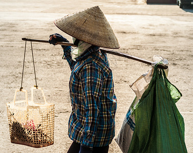 越南人戴帽 肩膀上带着枷锁在街上背景图片