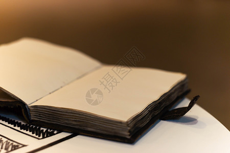 手工制作的魔法笔记本 封面上有塔符号 皮革封面和里面的手工床单 笔记本的第一页有 12 个星座 非常模糊的背景 软焦点放在笔记本背景图片
