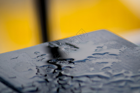 黄色背景的雨后黑木桌 许多水滴在桌子上 血缘是黑色的背景图片